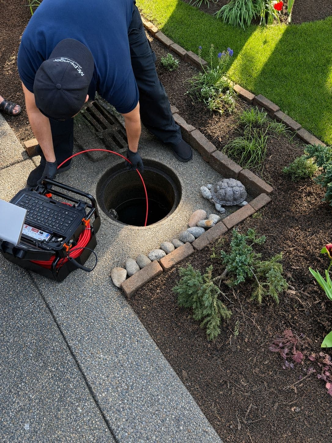 Mr. Plunger plumber running a drain camera into an outdoor cleanout to diagnose a blockage