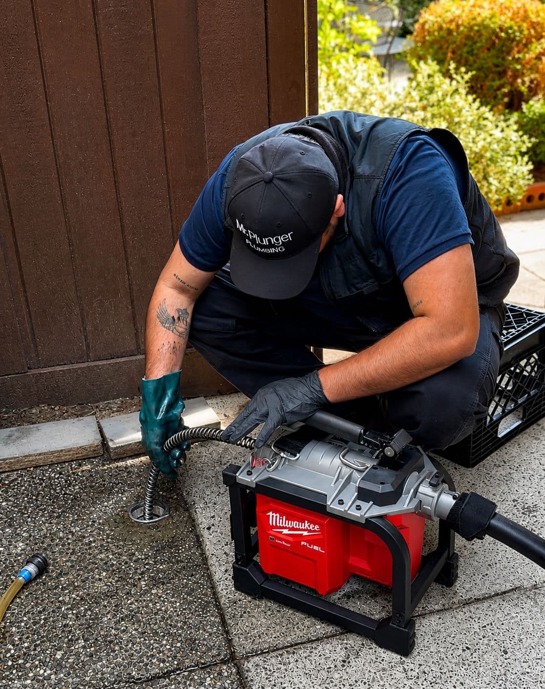Mr. Plunger plumber clearing a drain with a Milwaukee auger