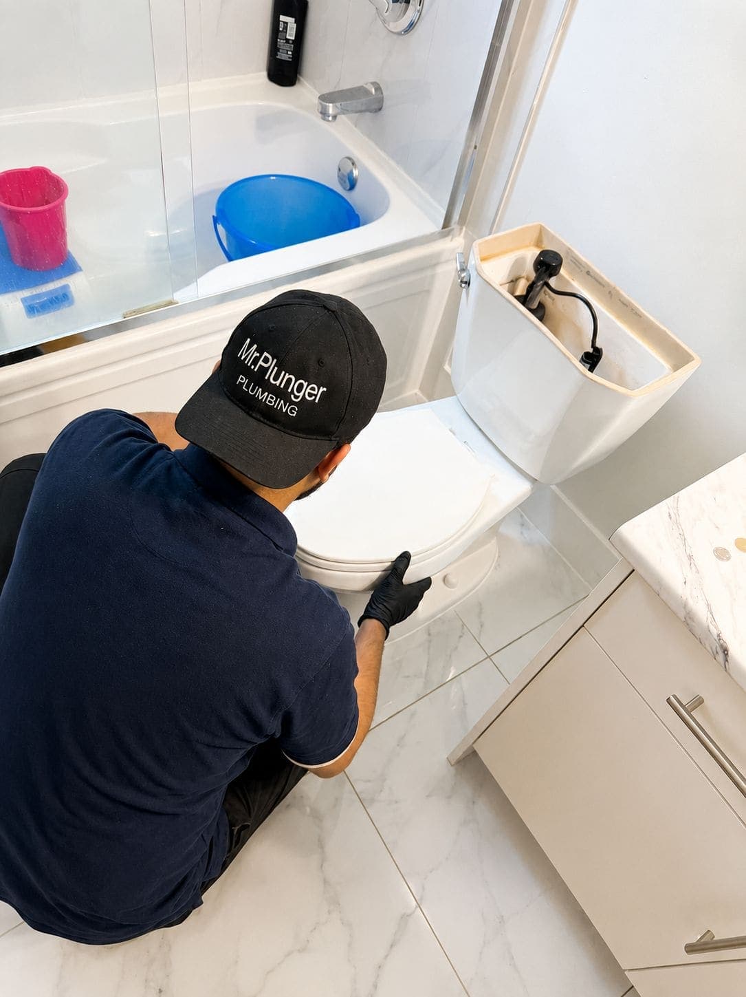 Mr. Plunger plumber repairing a toilet in a customer's bathroom