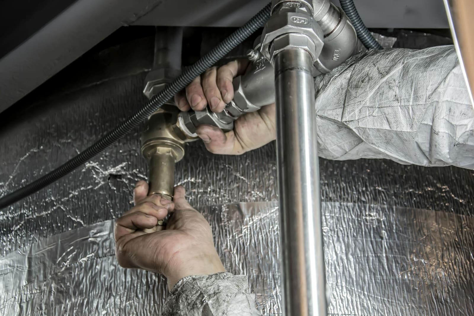 Plumber's hands installing a new water supply pipe — the hands-on stage of a service-line replacement